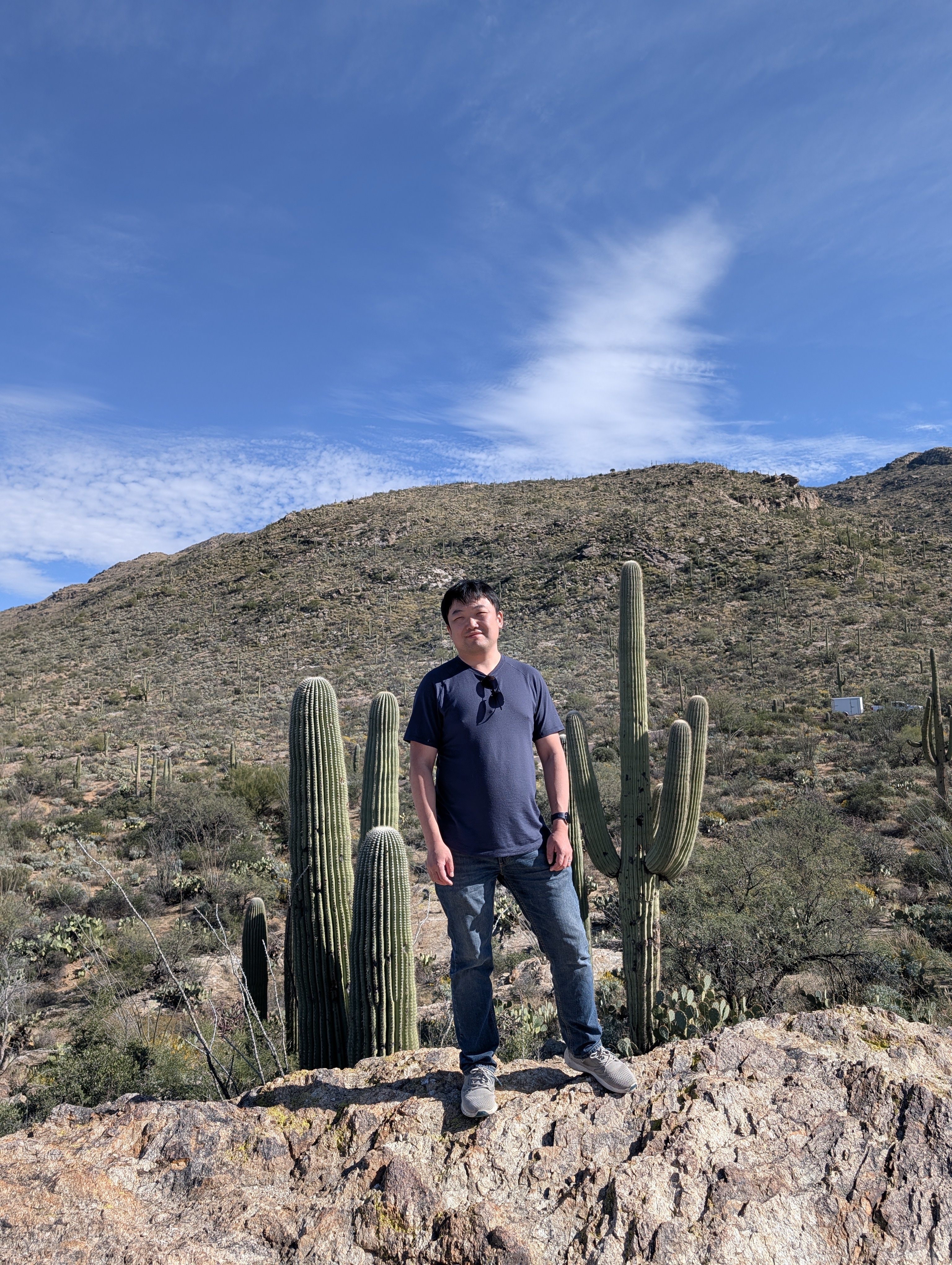 Nick Yu standing among saguaro cacti in the desert